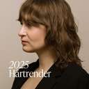 Kvinna med halvlångt brunt vågigt hår och lugg som illustrerar hårtrender 2025 med boho inspirerad bob och lob hos Green Heads.