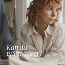 Kvinna med lockigt rött hår i badrum som funderar över hur ofta och hur hon ska tvätta håret på rätt sätt.